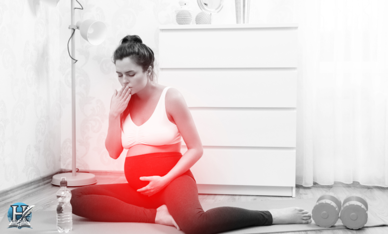 امرأة حامل تجلس على الأرض وتغطي فمها بيدها، تبدو متأثرة برائحة كريهة.