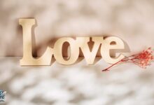 حب مكتوب بكلمة Love بجانب وردة حمراء – تعبير بصري عن مشاعر الحب والرومانسية.