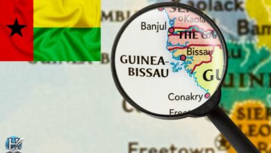 خريطة تُظهر موقع دولة غينيا بيساو في غرب إفريقيا تحت عدسة مكبرة، مع ظهور علم الدولة في الزاوية.