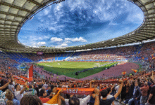 مشجعون في ملعب أوروبي ضخم يشجعون فريقهم خلال مباراة كرة قدم، في مشهد يعكس الشعبية الكبيرة للعبة في أوروبا.