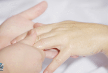 يد أنثوية بأصابع نحيفة وأنيقة تظهر على خلفية ناعمة، تعبّر عن العناية بالجمال وتنحيف الأصابع.